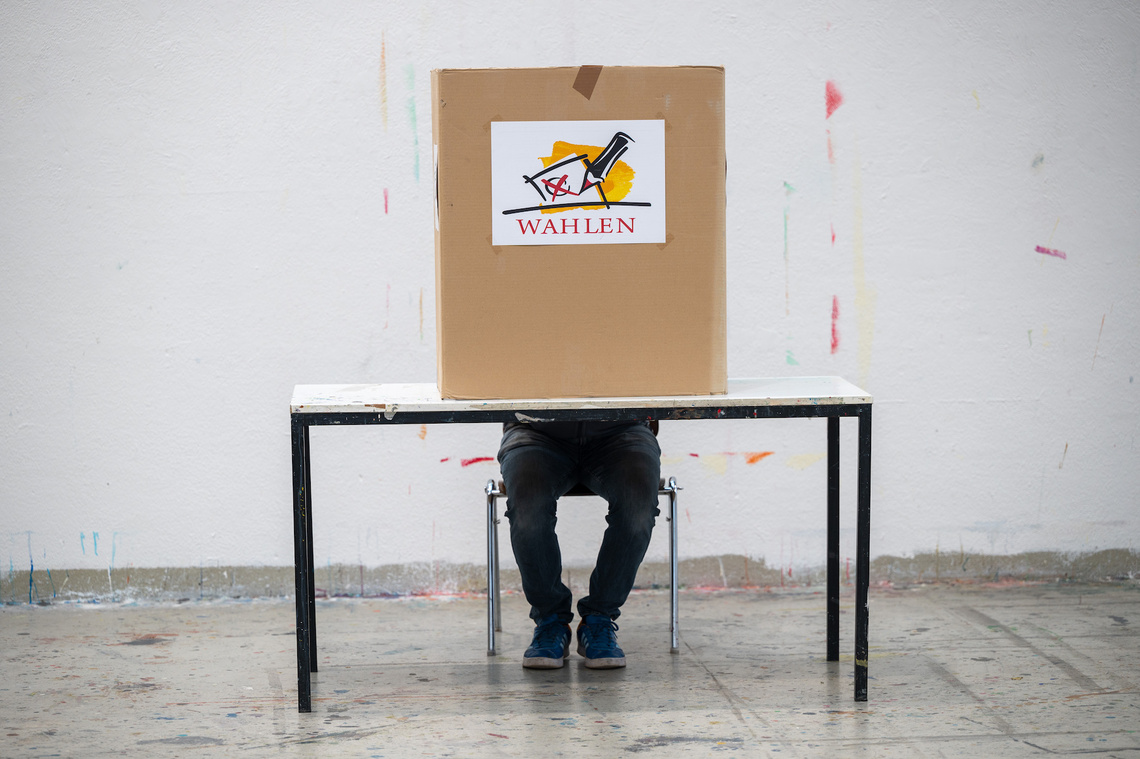 Wahlkabine, hinter der ein Wähler sitzt